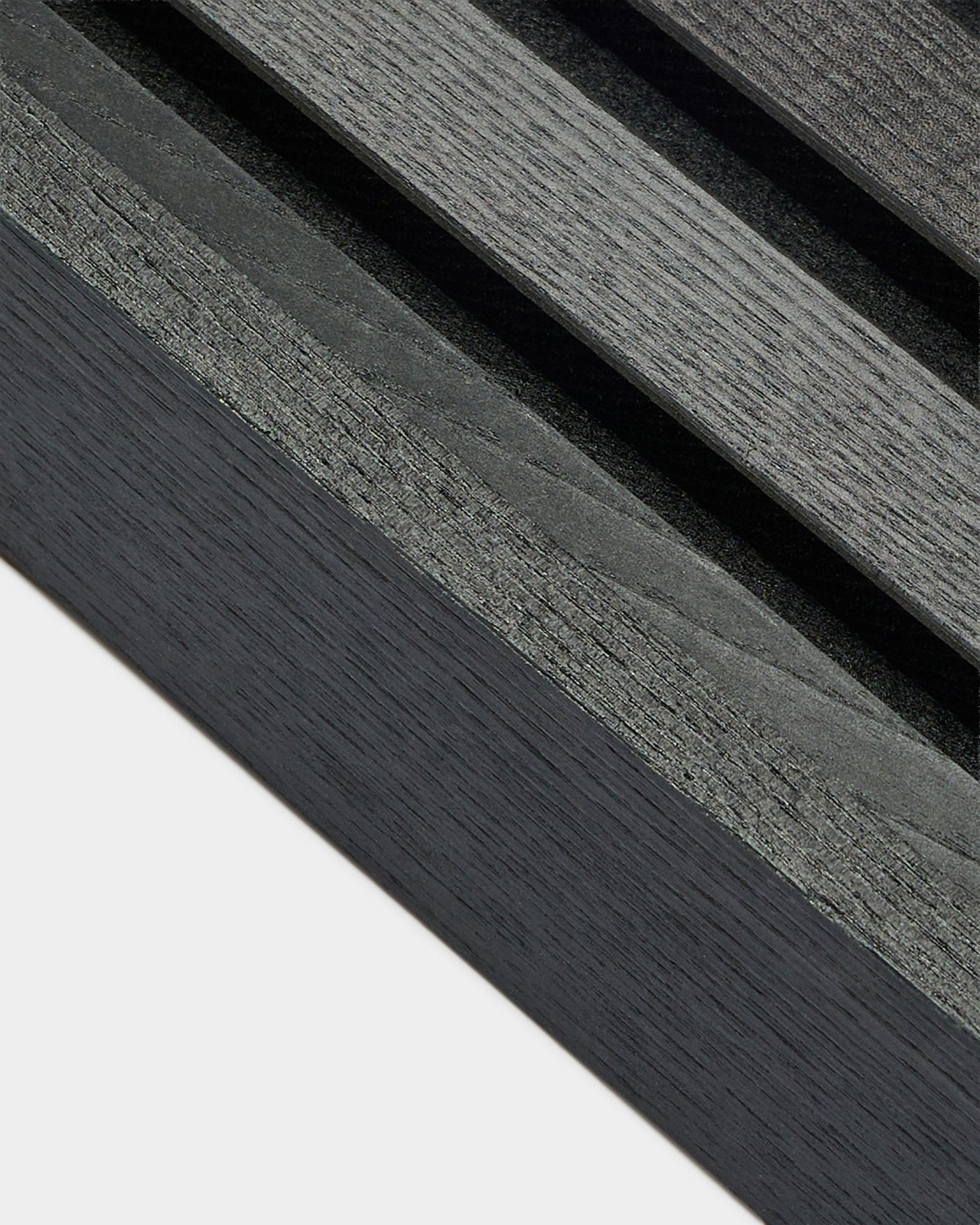 Close-up van de WoodUpp Akupanel eindlamel in Black essen (6,7 cm), met een donkergrijze houtnerf op een lichte basis, ontworpen voor Nordic Akoestisch paneel installaties.